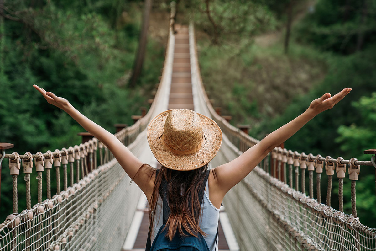 back view of woman crossing a bridge through a jungle